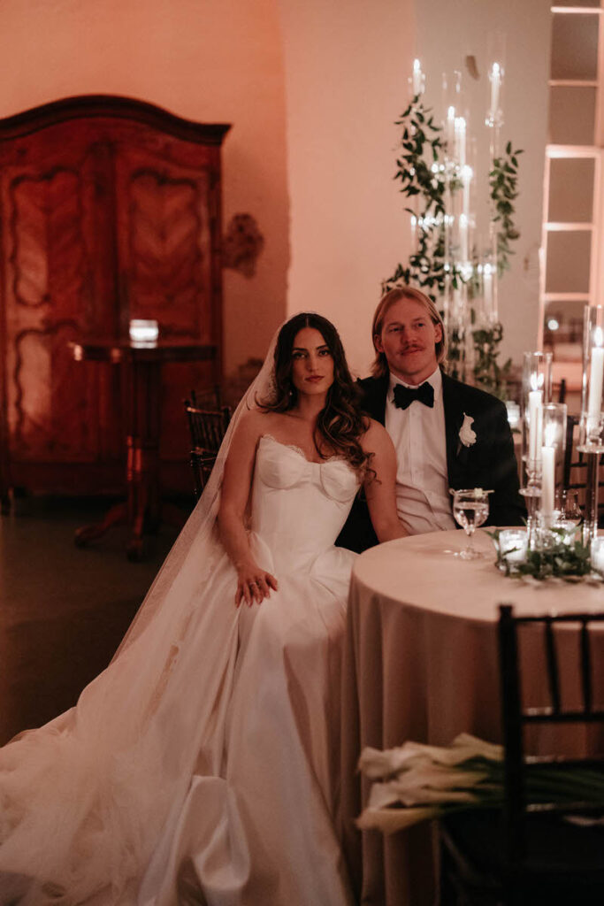 A newlywed couple sitting together at a wedding reception table