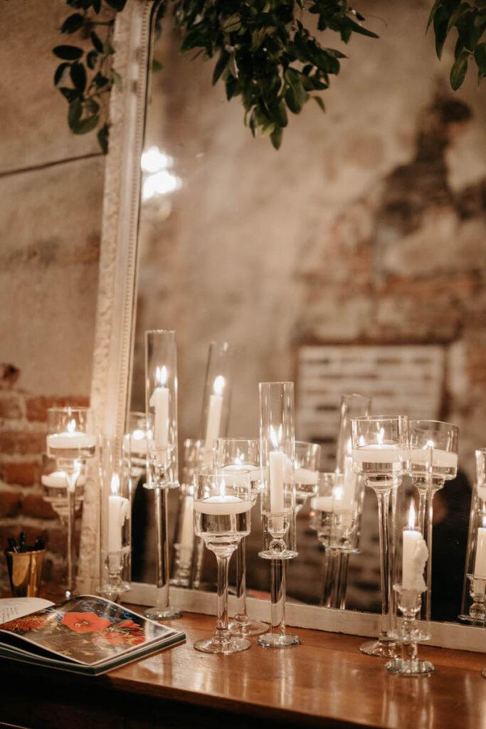 Small candles in tall glasses in front of a mirror