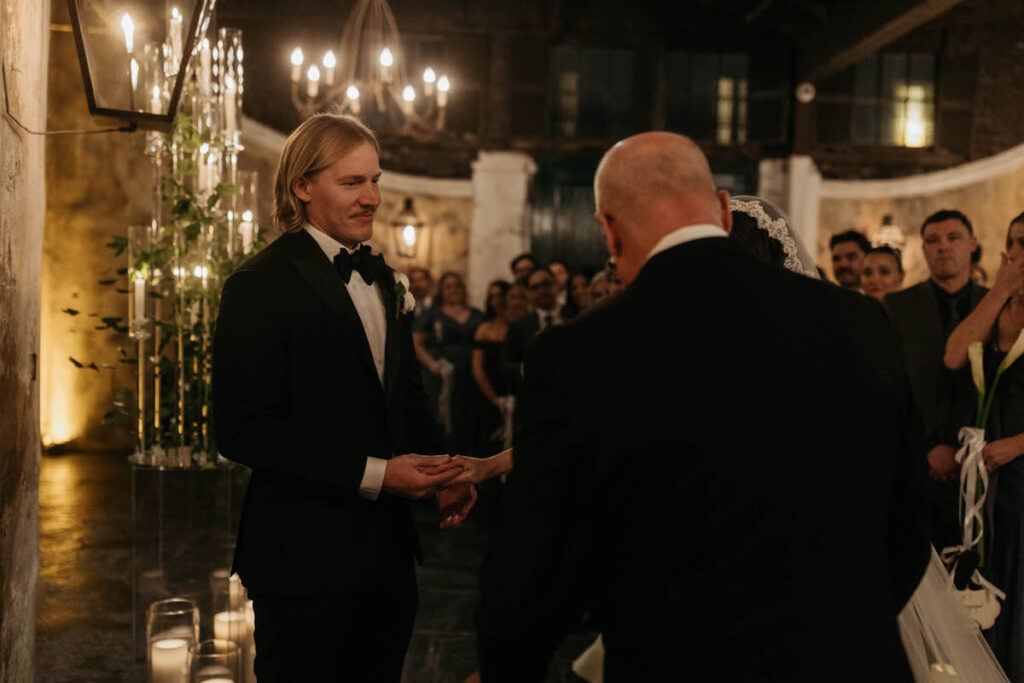A person holding their partner's hand as they slide a ring on it during their wedding ceremony
