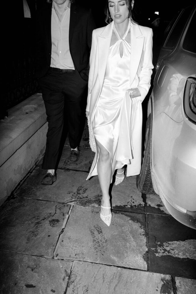 A couple holding hands and walking between a car on a street