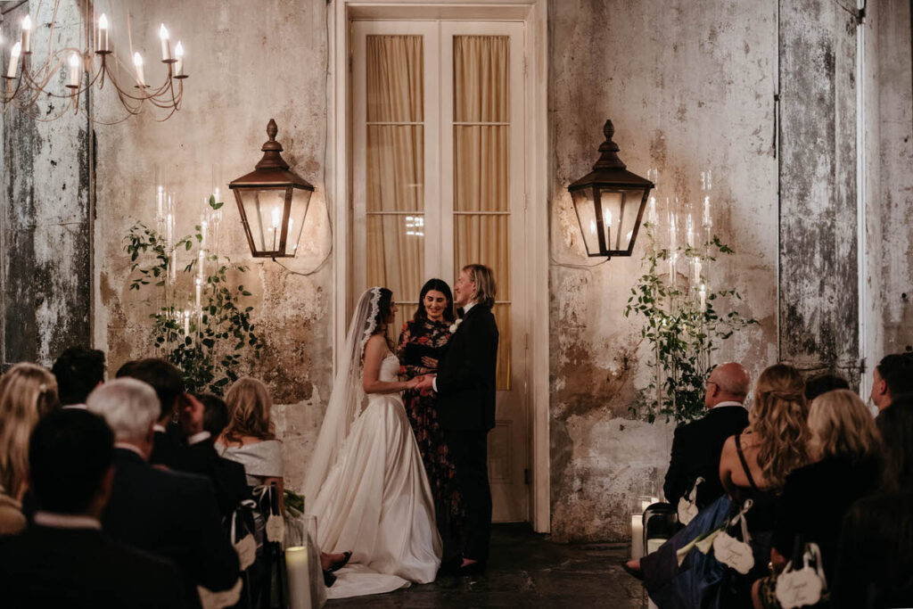 A wedding couple standing up and holding hands as they say their vows