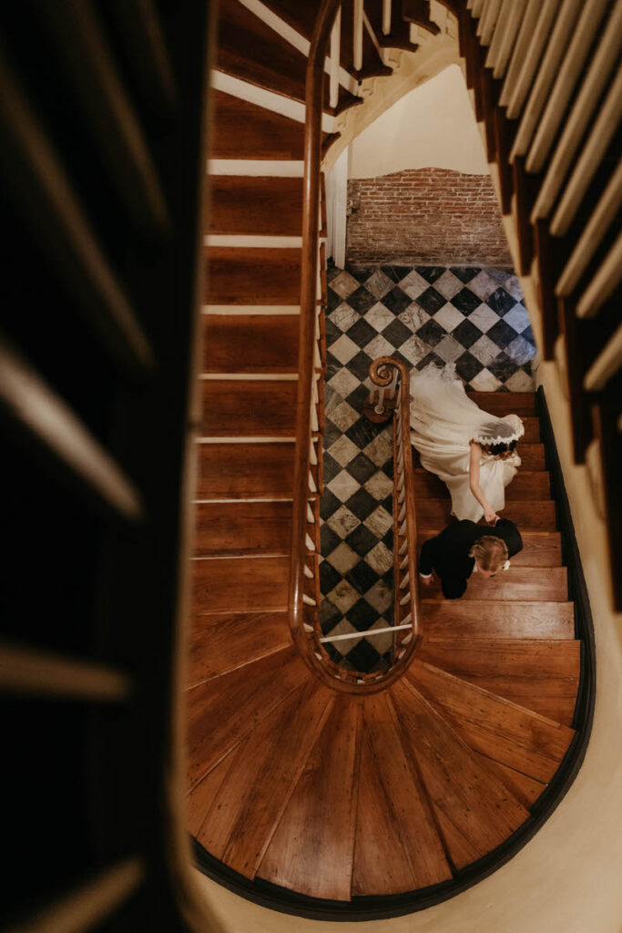 View looking down a staircase of a wedding couple walking up it