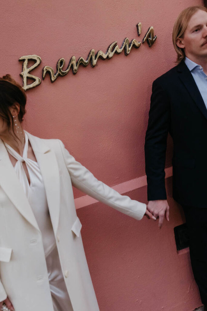 A couple holding hands in front of a building with a sign that says "Brennan's"