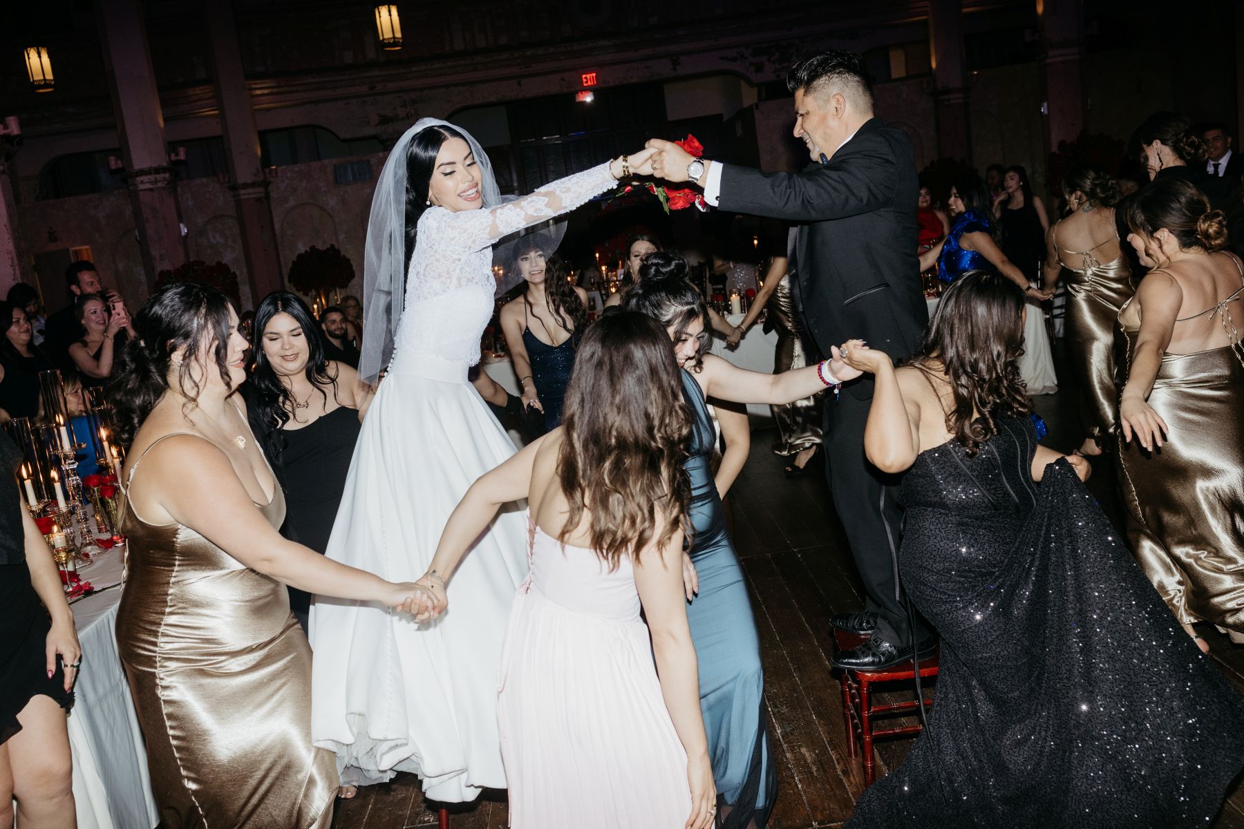 a couple dancing on chairs at their wedding reception with their wedding guests 