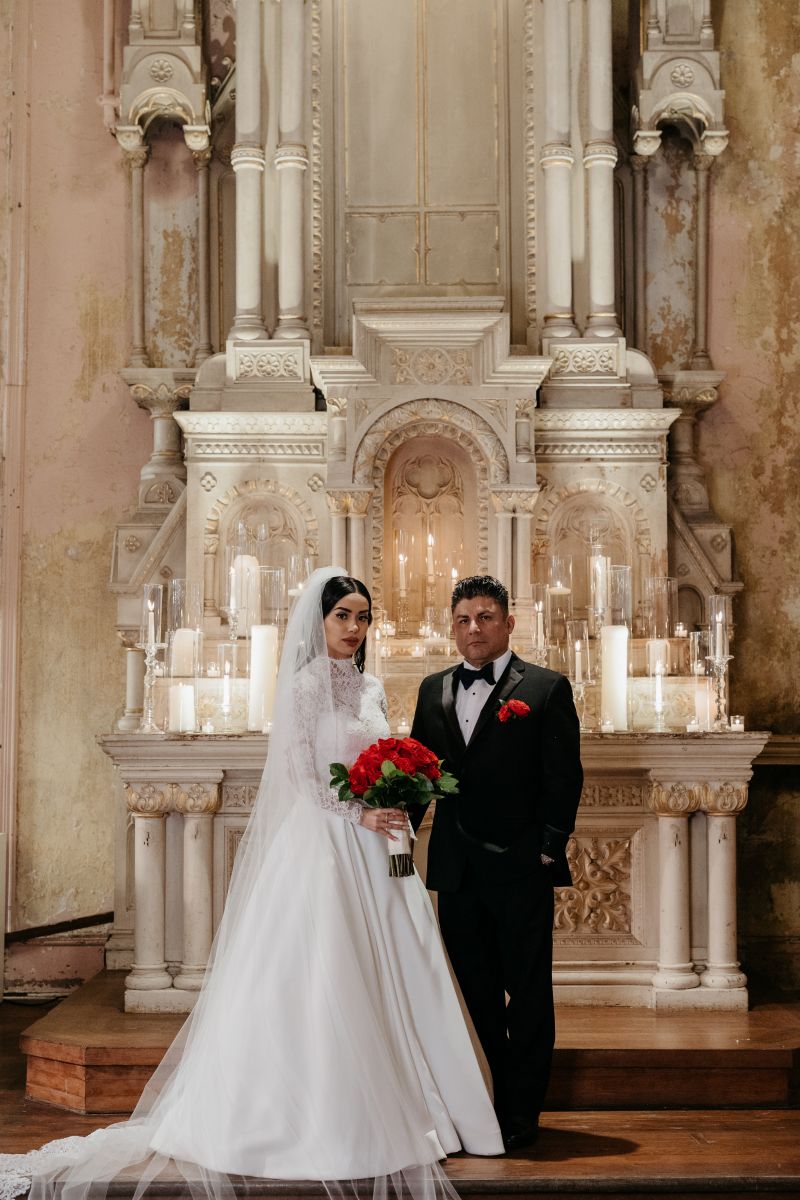a couple standing next to each other and posing in front of an altar 