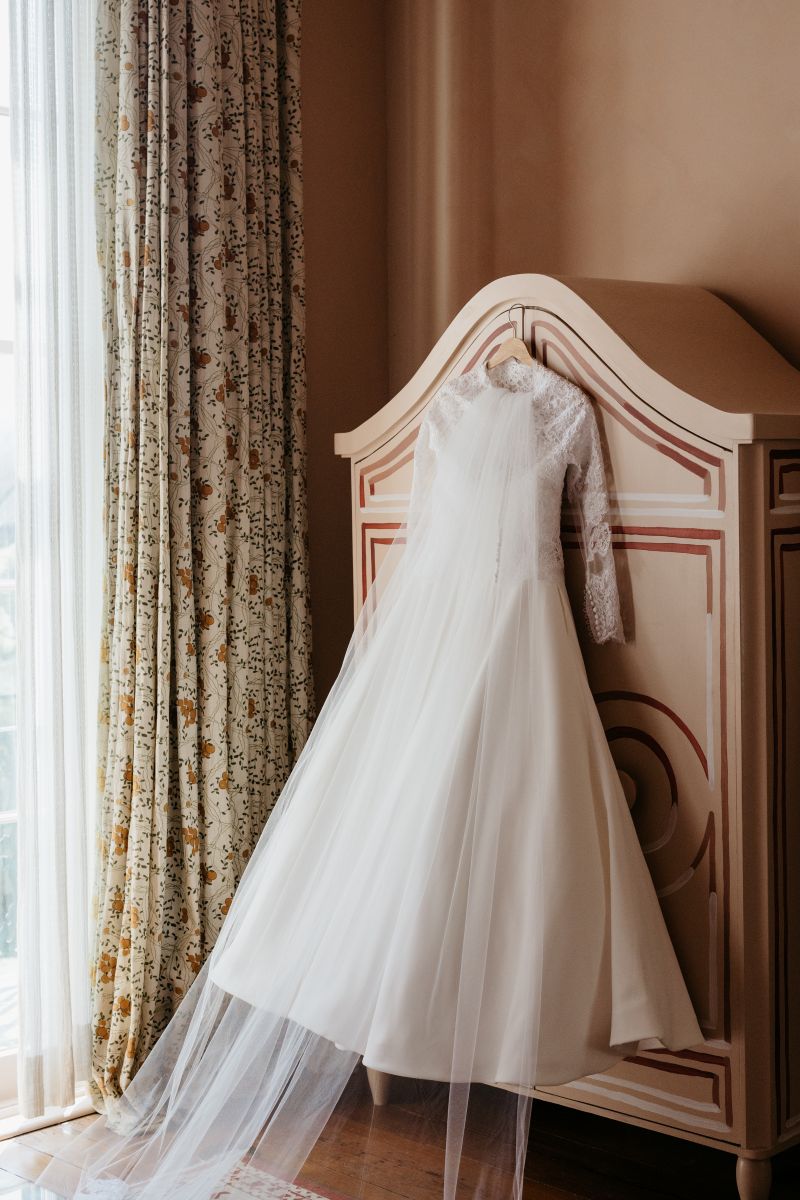 editorial style wedding photography of a wedding dress hanging on the back of a closet with the veil 