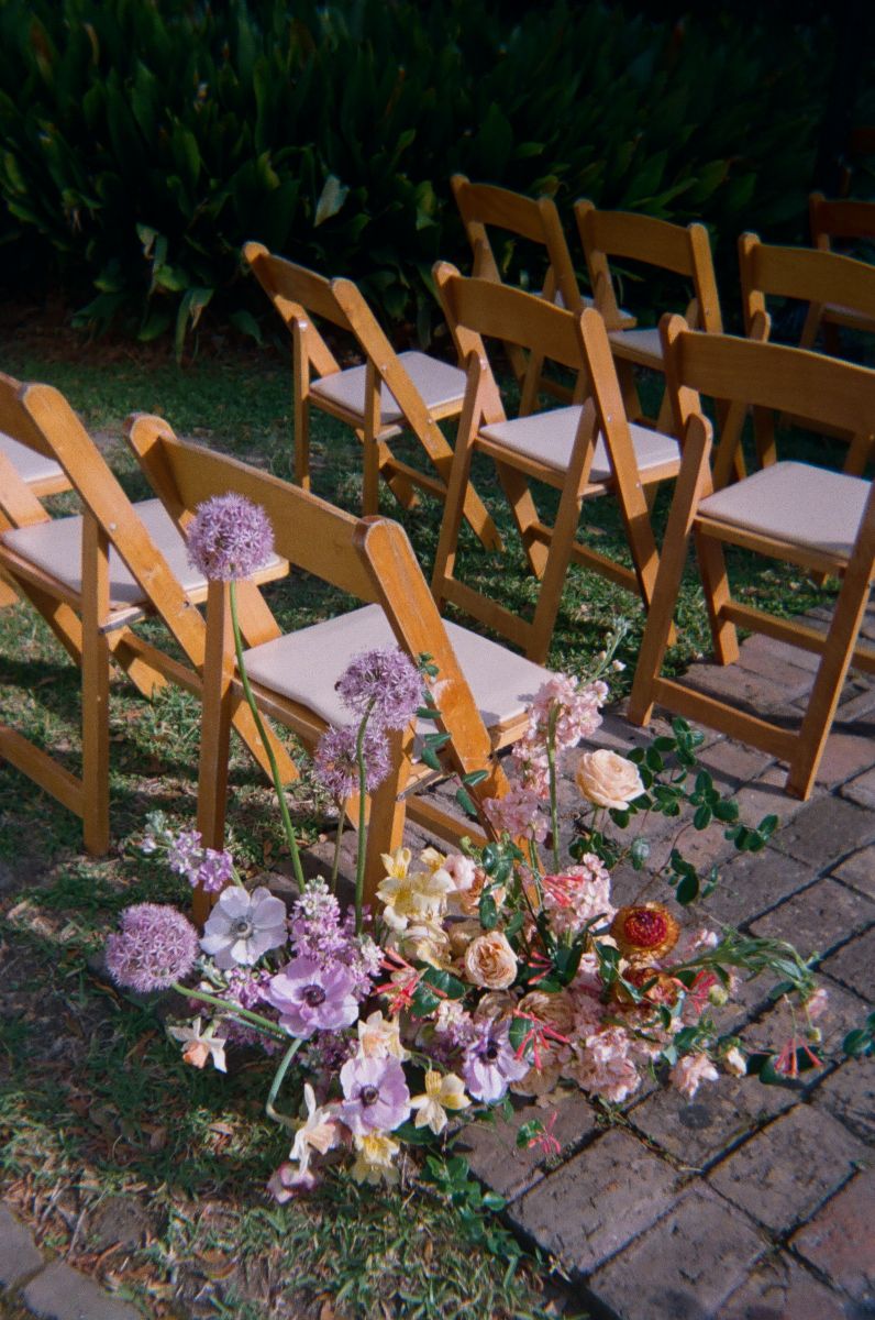a colorful and whimsical floral arrangement next to chairs set up for a wedding ceremony