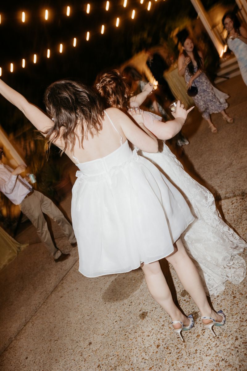 two women dancing together at their wedding reception on the back patio of derbes mansion in new orleans