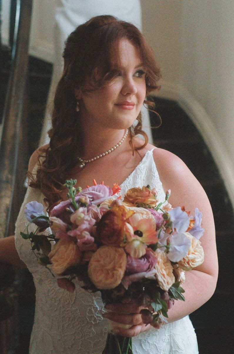 a woman in a white wedding dress looking off to the side and holding a bouquet