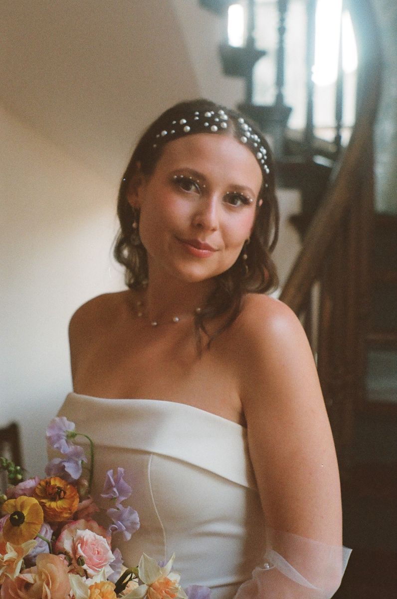 a woman in a white wedding dress smiling softly and holding a bouquet of flowers