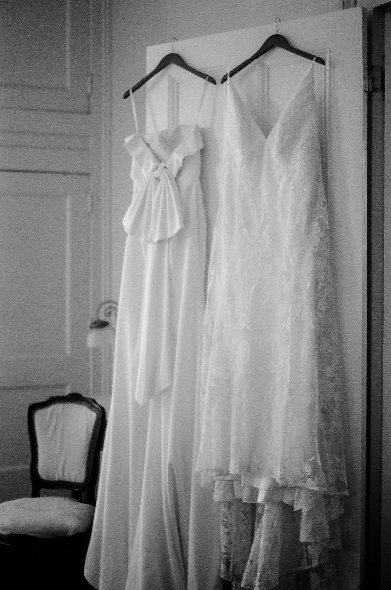 two white wedding dresses hanging together on the back of a door