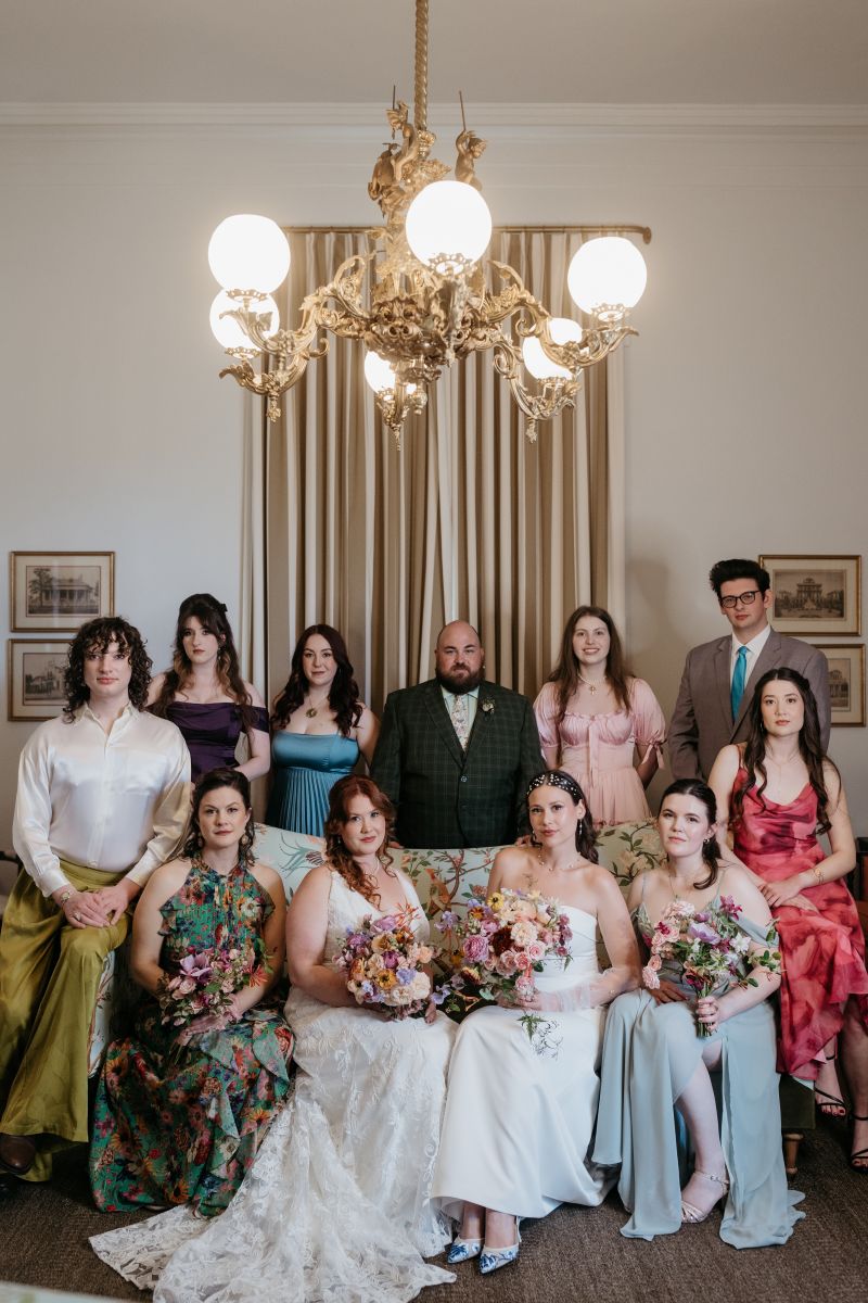 family members of the brides and two brides sitting inside of derbes mansion