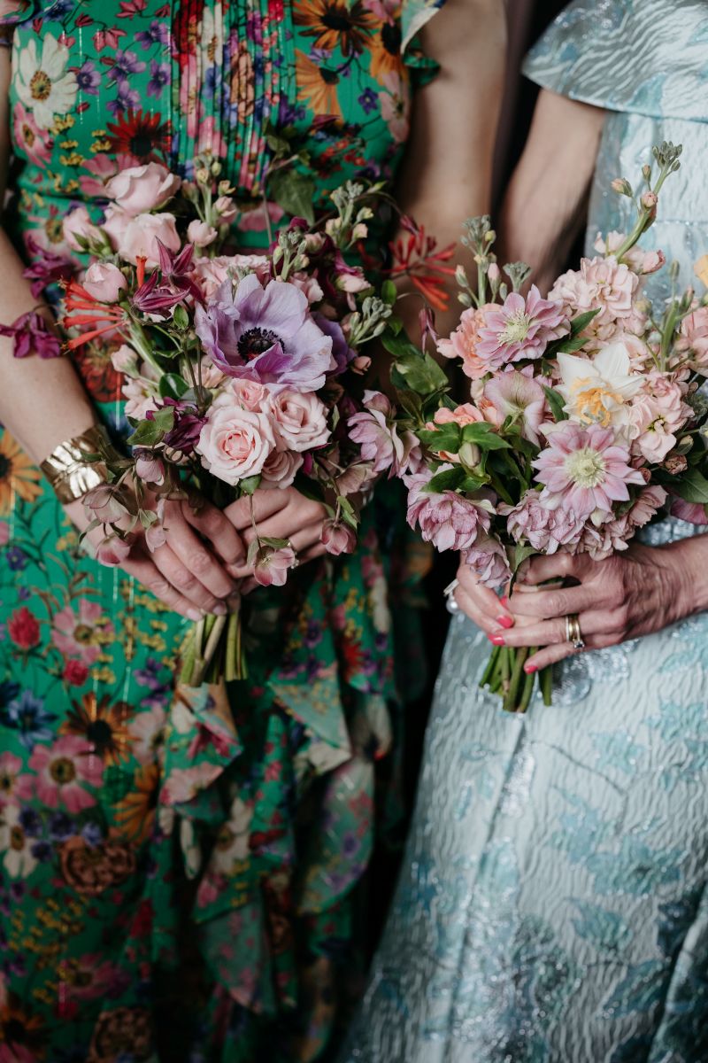 two women holding colorful floral bouquets