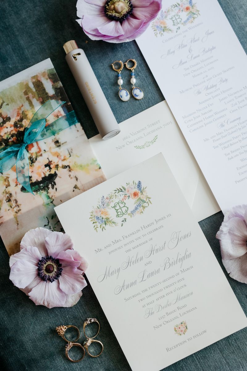 wedding details on a wooden table including rings, invitations, and flowers