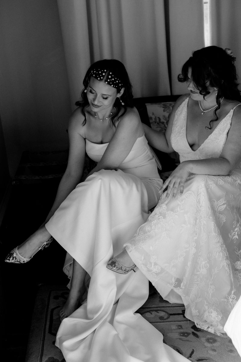 two women sitting on a couch together getting ready for their wedding