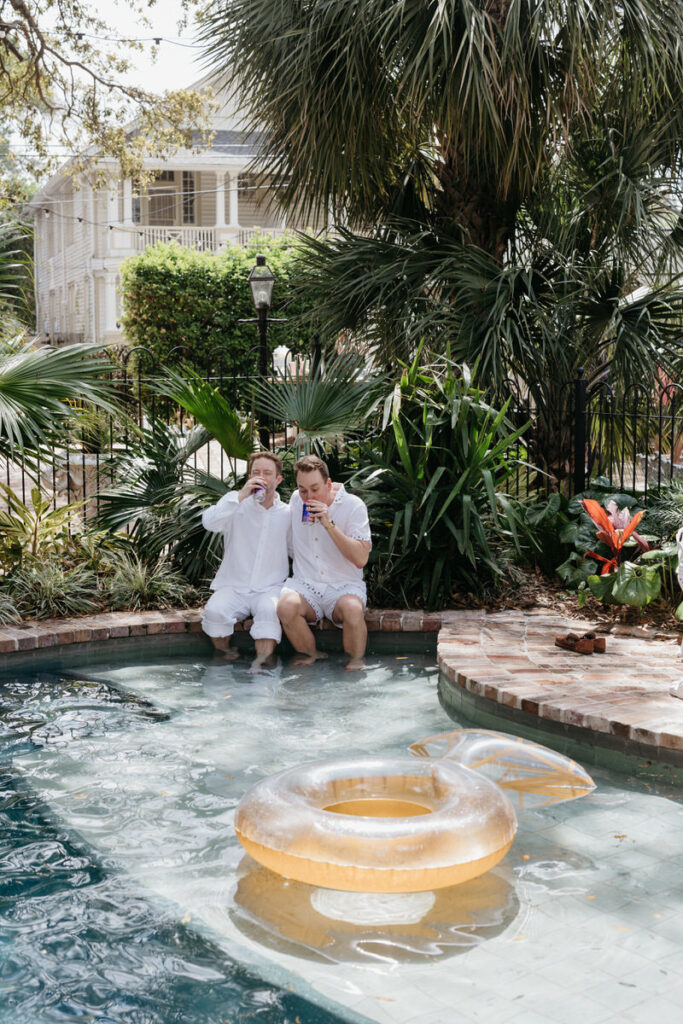 Two people drinking with their feet in a pool 