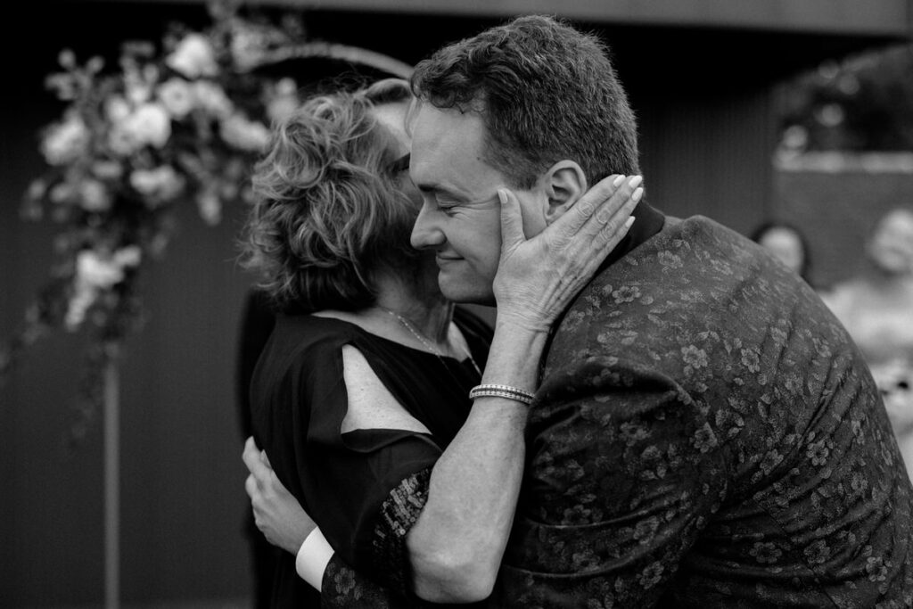 An older person hugging a newlywed closely 