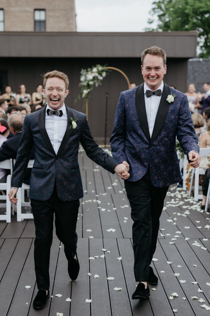 A wedding couple holding hands and walking back up the aisle 