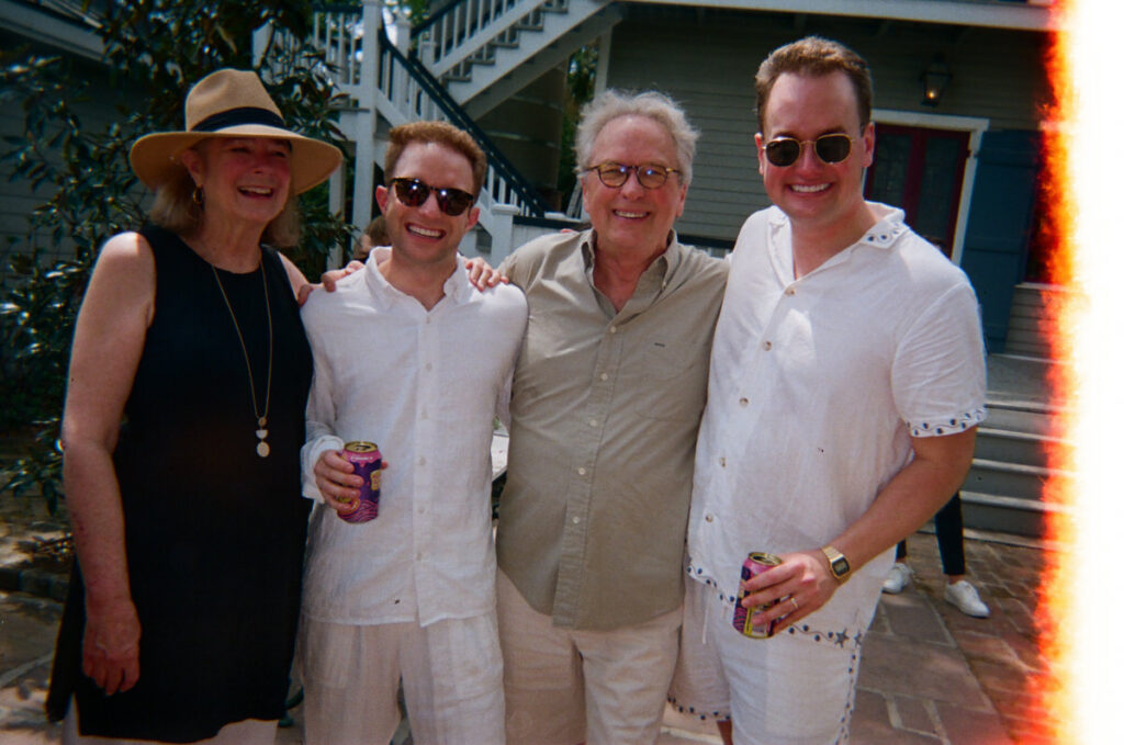 Film image of a group of people with their arms around each other smiling 
