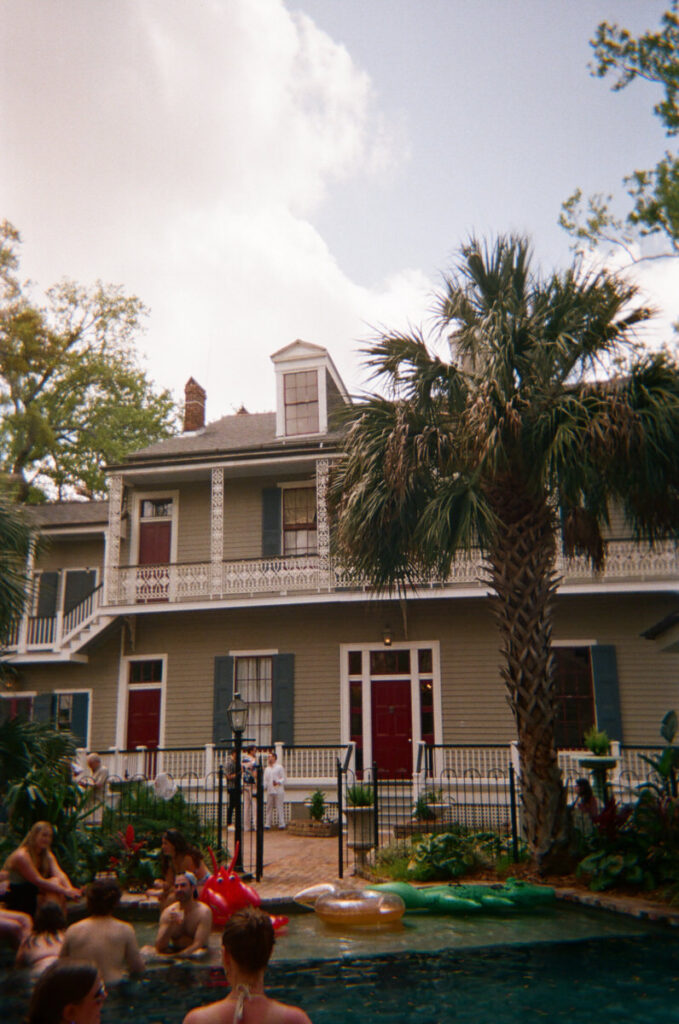 A large house with a pool out front filled with people 