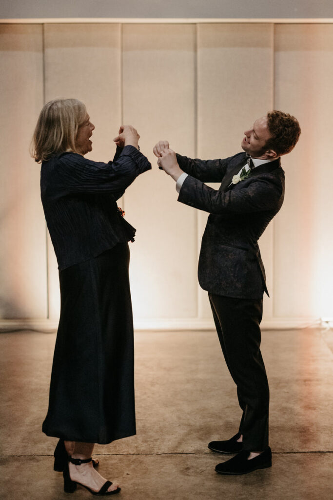 Two people standing together holding hand hearts out towards each other 