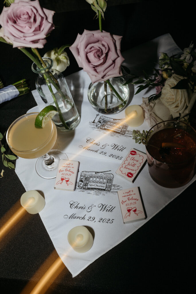 Customized napkins, booklets, drinks, and flowers laid out on a table 