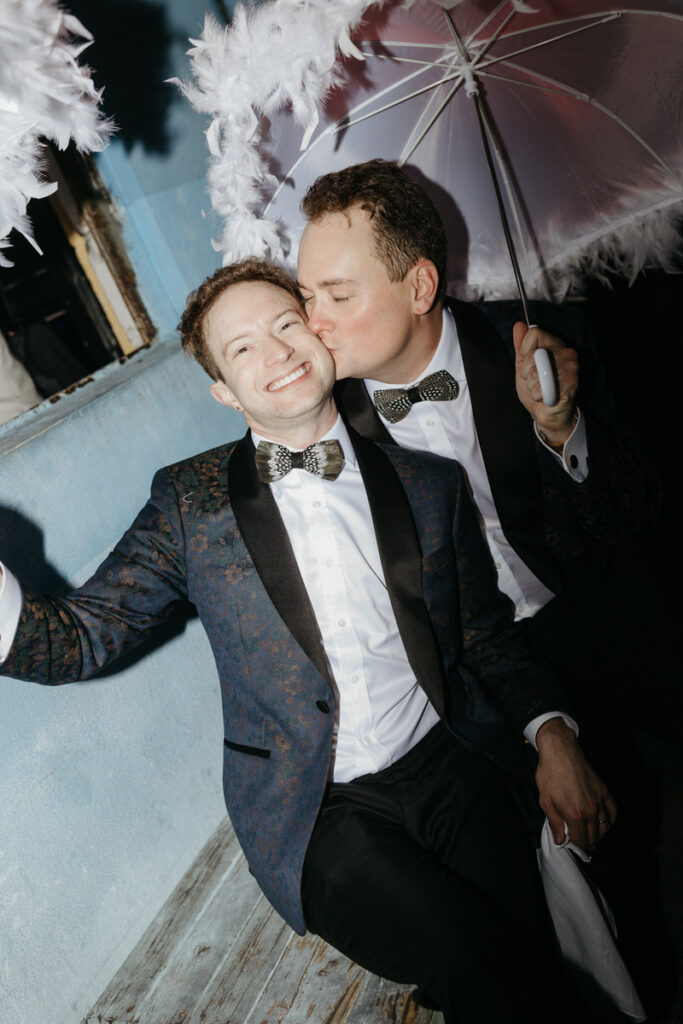 A person kissing their partner's cheek while they smile 