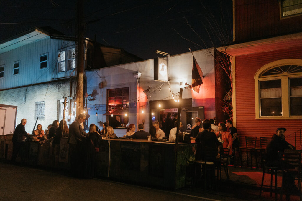 Wedding guests sitting in a small outdoor area at a bar 
