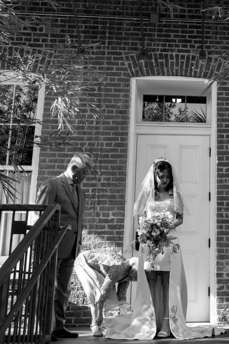 a woman standing on steps as her mother arranges her wedding dress before her wedding ceremony