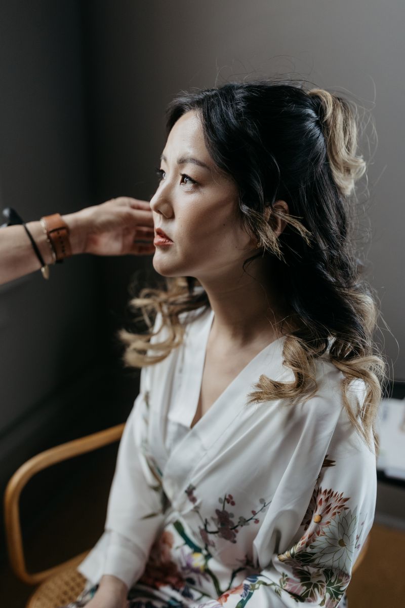 a woman wearing a robe getting ready for her wedding