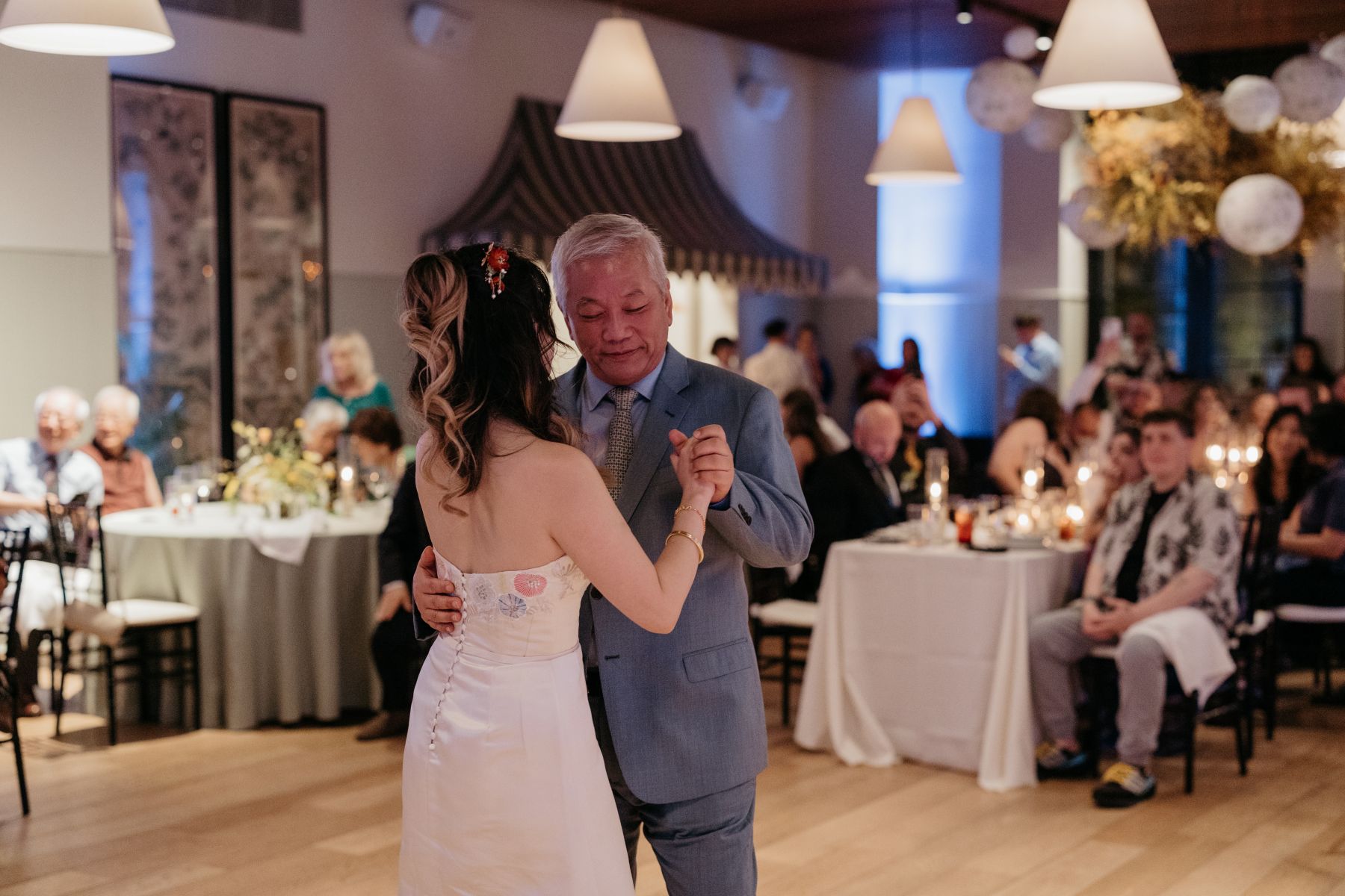 a woman in a white wedding dress dancing with her dad at her wedding reception